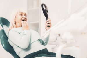 Old woman in dentist's chair looking at her new teeth